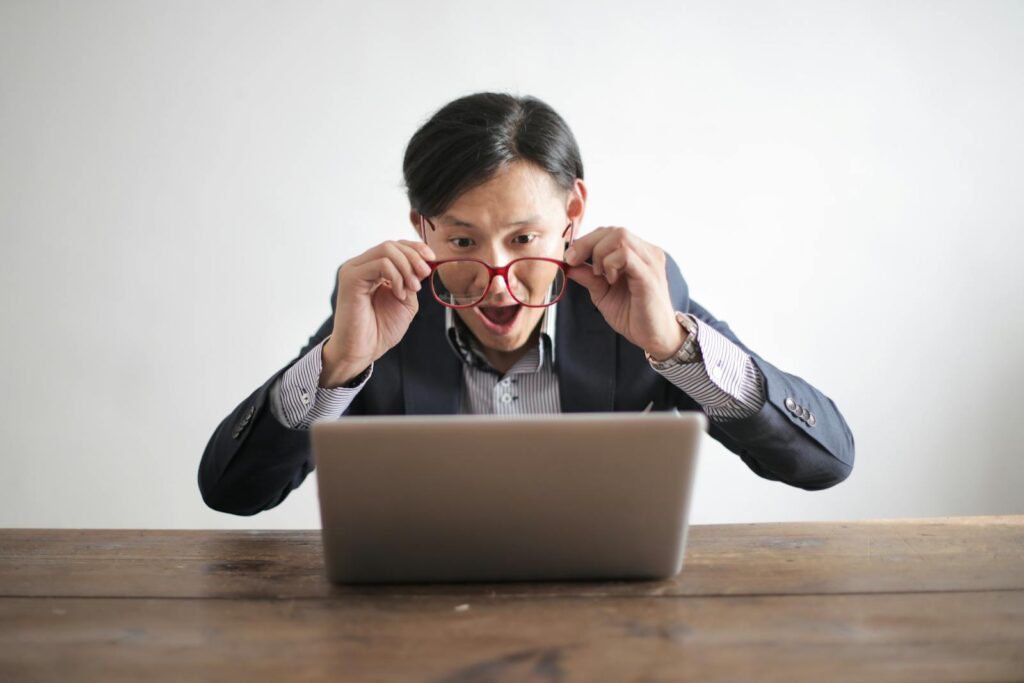 Un homme surpris en costume regarde un ordinateur portable, exprimant son incrédulité à l'intérieur.